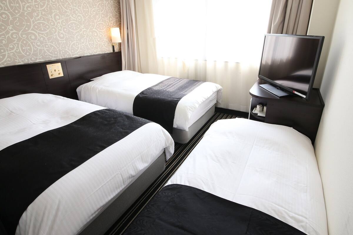 Ein Hotelzimmer mit zwei Betten, einem Fernseher und einer Bedienkonsole an der Wand.