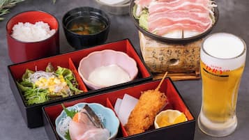 A meal with rice, salad, and various fish dishes, accompanied by a glass of beer and a bowl of soup.