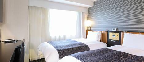 Habitación de hotel con dos camas, un escritorio, un teléfono y una ventana con cortinas.