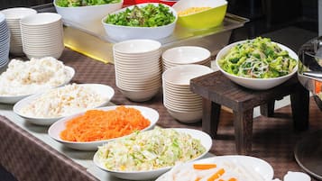 Una mesa de buffet con diversos platos, como ensaladas, arroz y verduras.