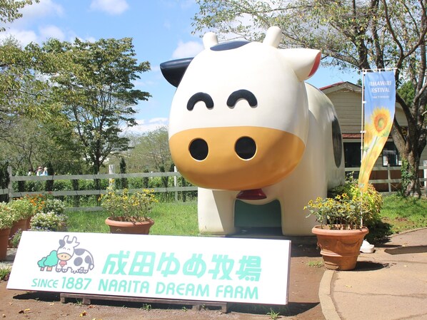 A large cow sculpture with a sign in front stating 'Since 1887 Narita Dream Farm'.