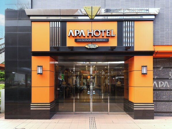 Exterior del hotel APA, de diseño moderno, con una entrada destacada y señalización clara.