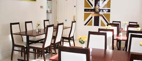 A dining area with wooden tables and chairs, a decorative wall piece, and a door with a 'no entry' sign.