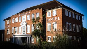 Et Kingsland Hotel med en traditionel murstensfacade, flere vinduer og en central indgang med et markise.
