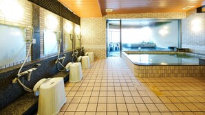 Baño público con varios lavamanos, un espejo grande y una zona de hidromasaje.