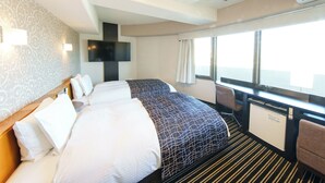 Habitación de hotel con dos camas, televisión, minibar y un ventanal grande con cortinas.
