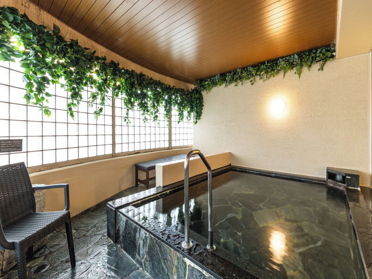 Zona de spa con bañera de hidromasaje, techo de madera y un banco.