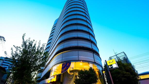 Un hotel moderno con fachada curva, varios pisos y un letrero llamativo del hotel.