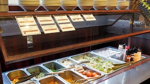 Un bufé con diversas opciones de comida y utensilios.