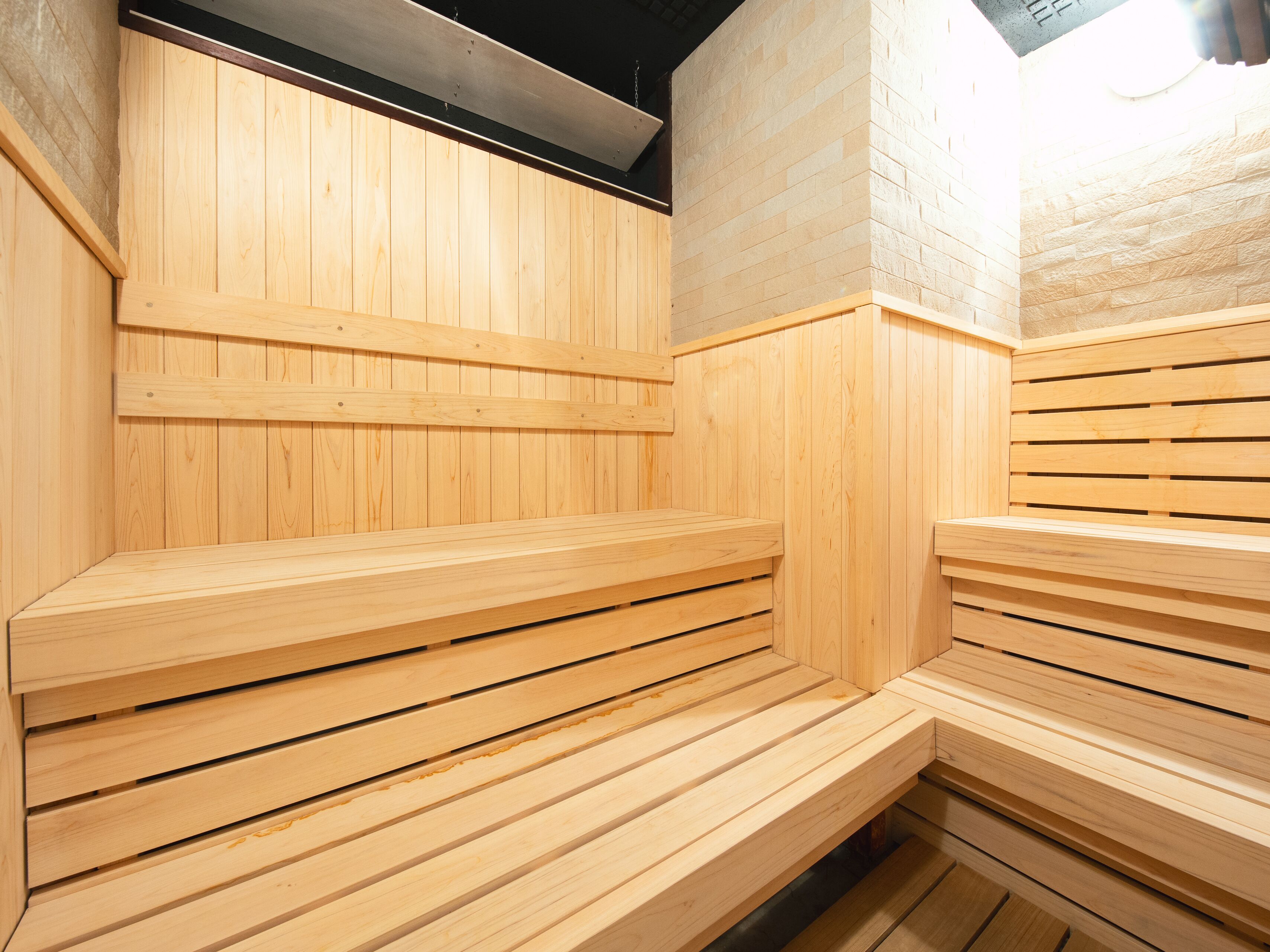 A sauna with wooden benches and a stone wall.