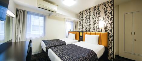 Habitación de hotel con dos camas, un escritorio y un armario.