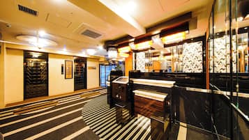 A hotel lobby with a check-in counter, seating area, and a staircase leading to another floor.