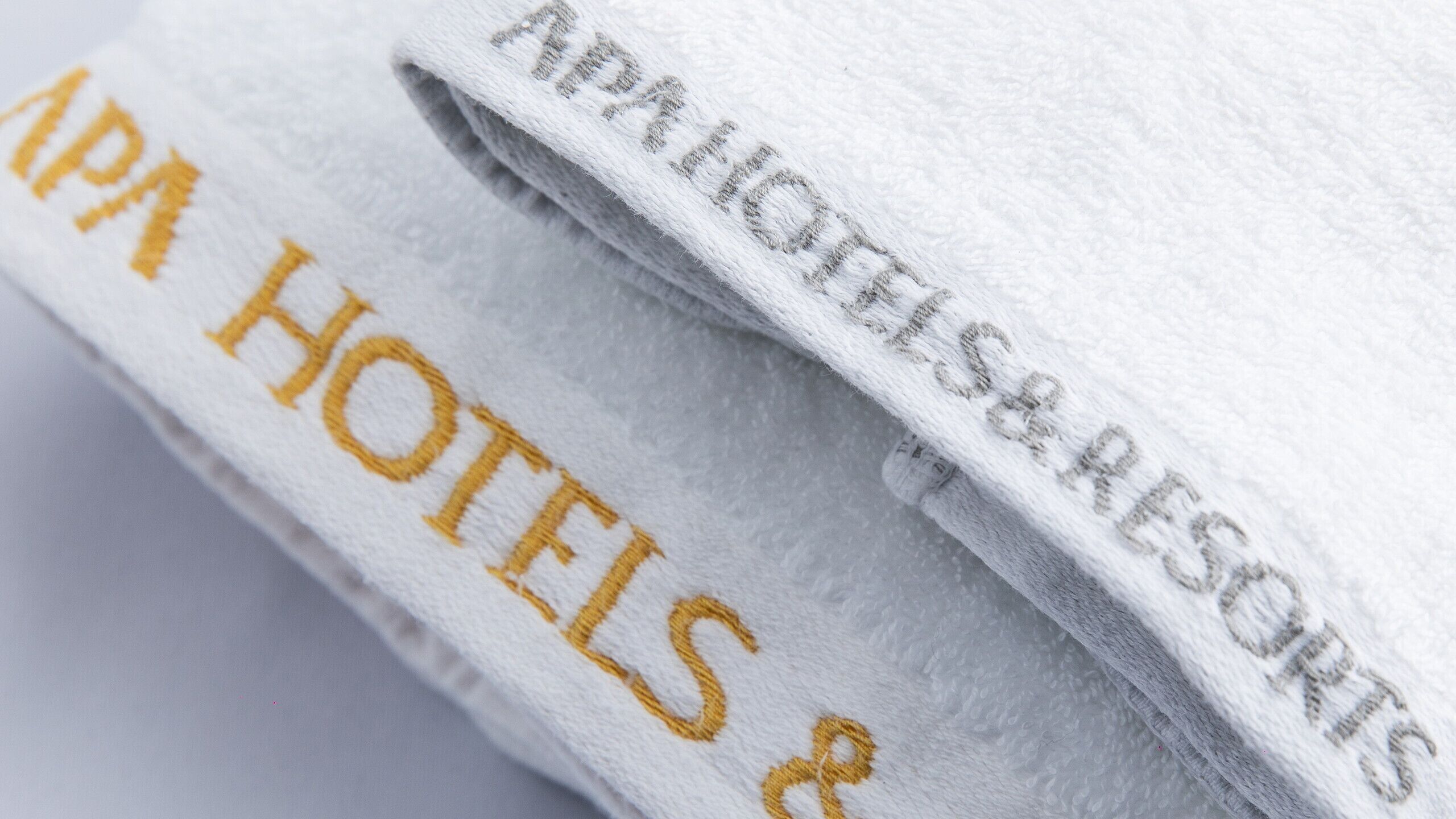 Taiteltu pyyhe, jossa on kirjailtu teksti: ”APATHOLIS RESORTS” ja ”APATHOLIS HOTELS & SPA”.