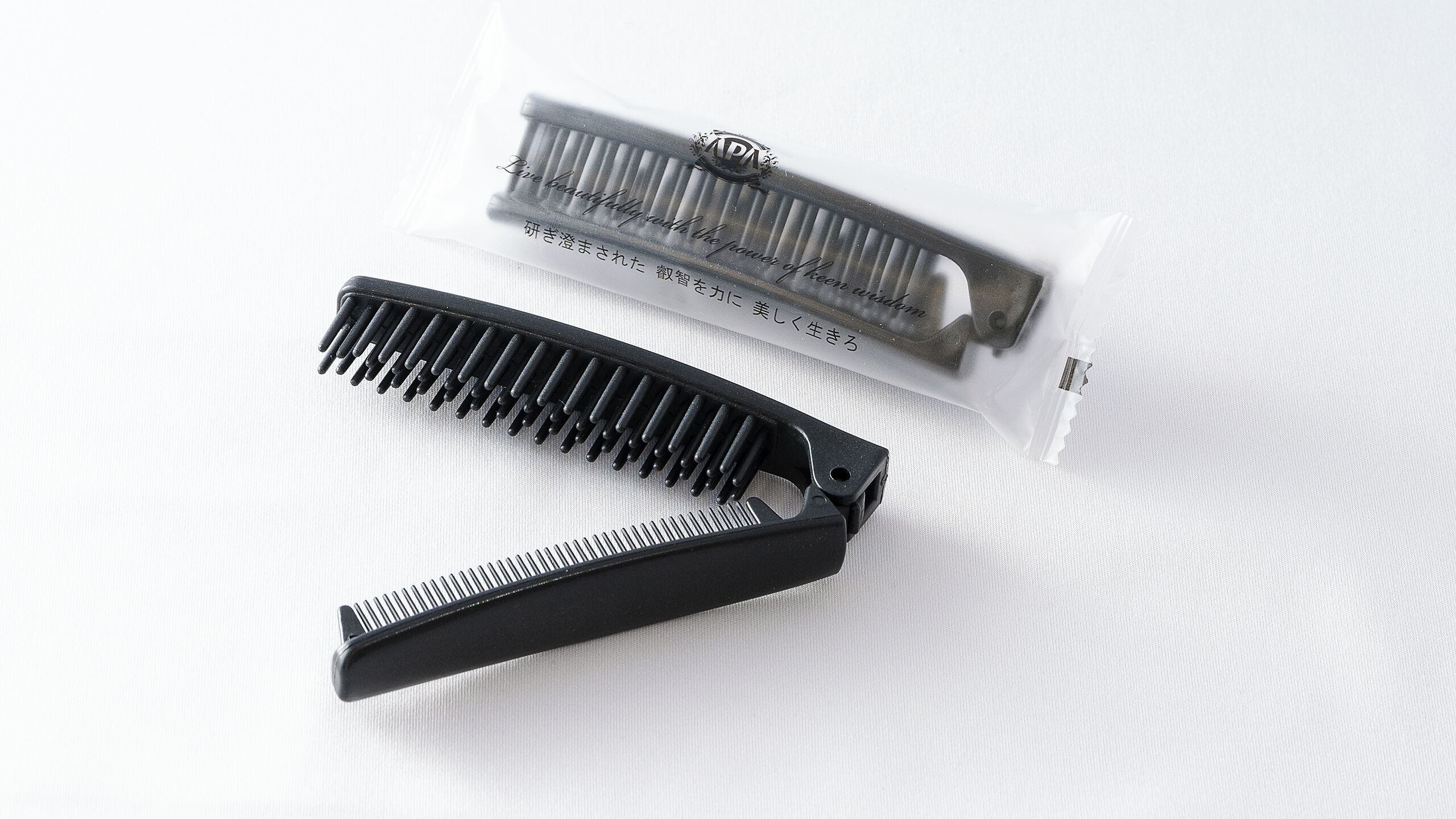 Twee zwarte kammen en een plastic verpakking met tekst erop.