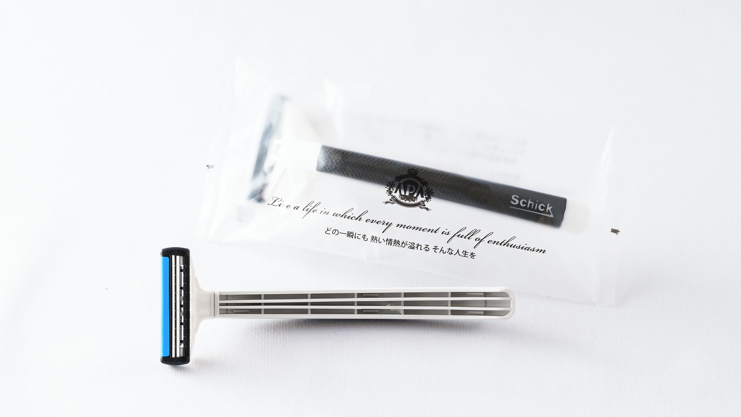 A Schick razor and its packaging on a white textured surface.