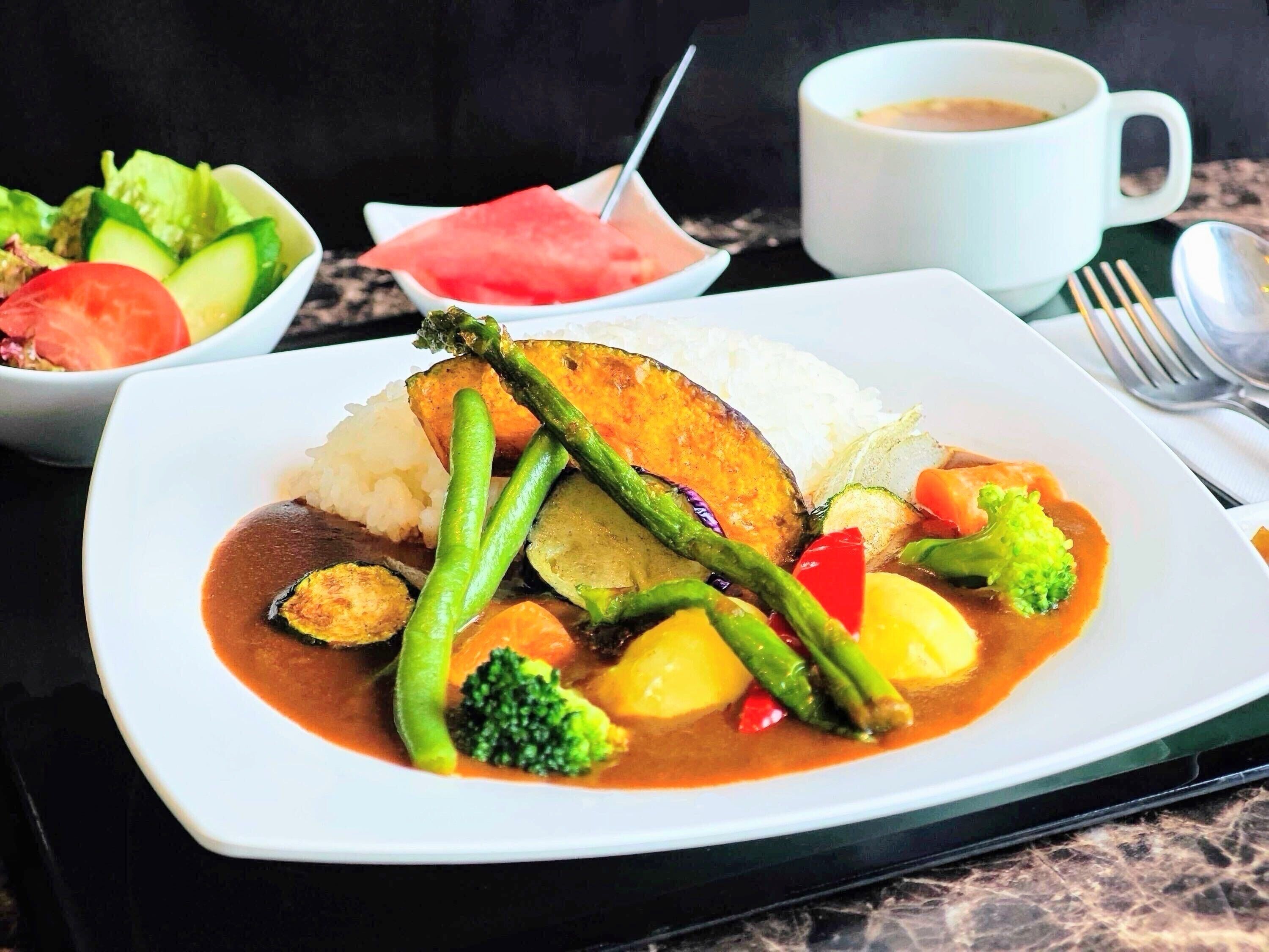 Une assiette de nourriture composée de riz, de légumes et d’une sauce semblable à une soupe.