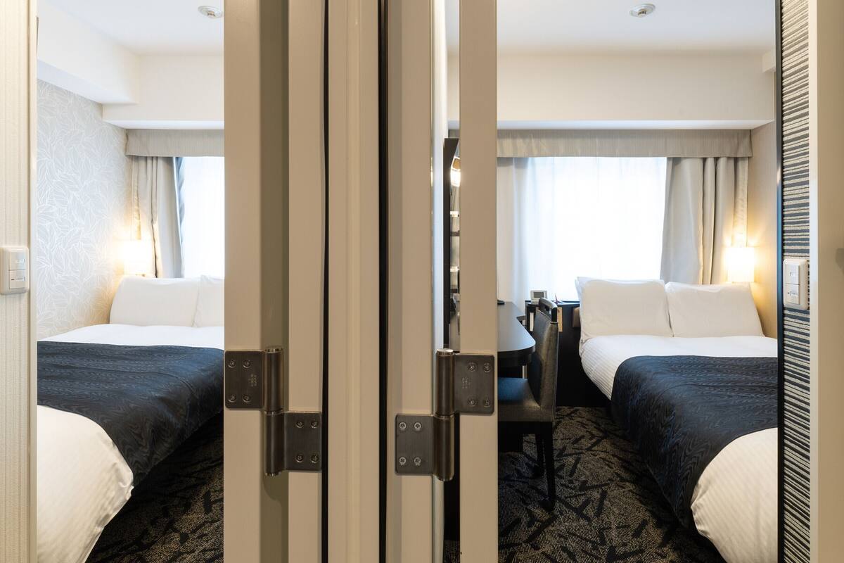 A hotel room with two beds, a desk, and a chair.