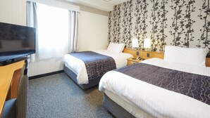 Habitación de hotel con dos camas, televisión y ventana con cortinas.