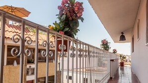 Un passadís amb sòl de rajola, barana metàl·lica i plantes en testos.