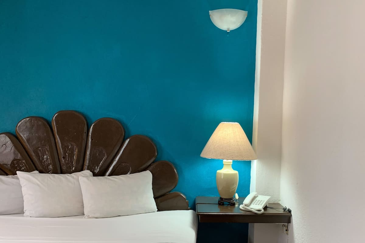 Een hotelkamer met een bed, een nachtkastje met een lamp en een telefoon.