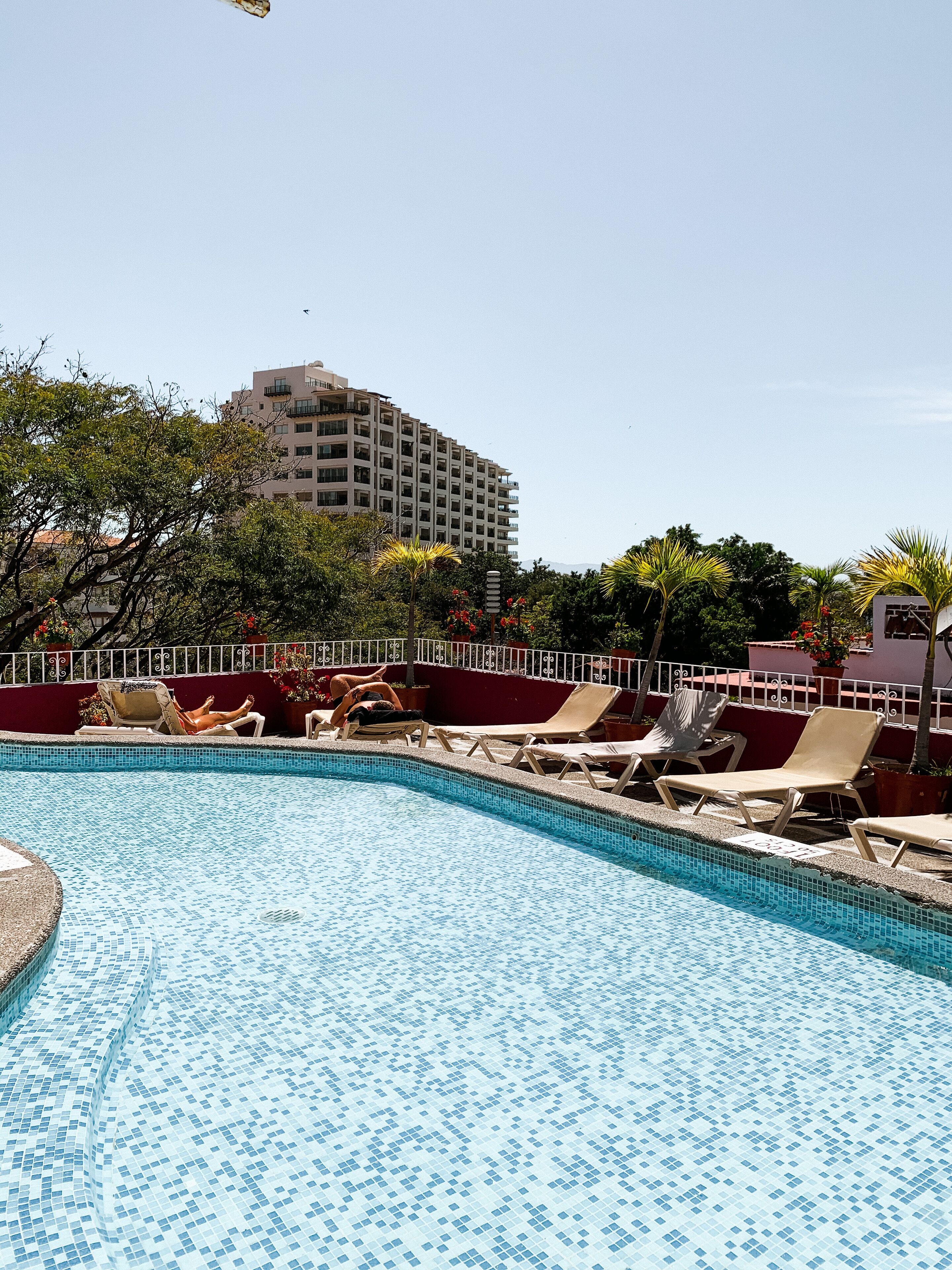 A swimming pool with lounge chairs and a building in the background.