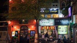 A restaurant with a dark entrance and illuminated signage, including "JIN SUN DAE" and "KASAI" names. - The White Hotel 8A Thai Van Lung (Ho Chi Minh City)