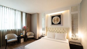 A hotel room with a large bed, two armchairs, a small table with a vase of flowers, and a wall-mounted artwork. - The White Hotel 8A Thai Van Lung (Ho Chi Minh City)