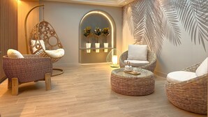 Un salón moderno con muebles de mimbre, una silla colgante y una pared con diseño de hojas de palmera.