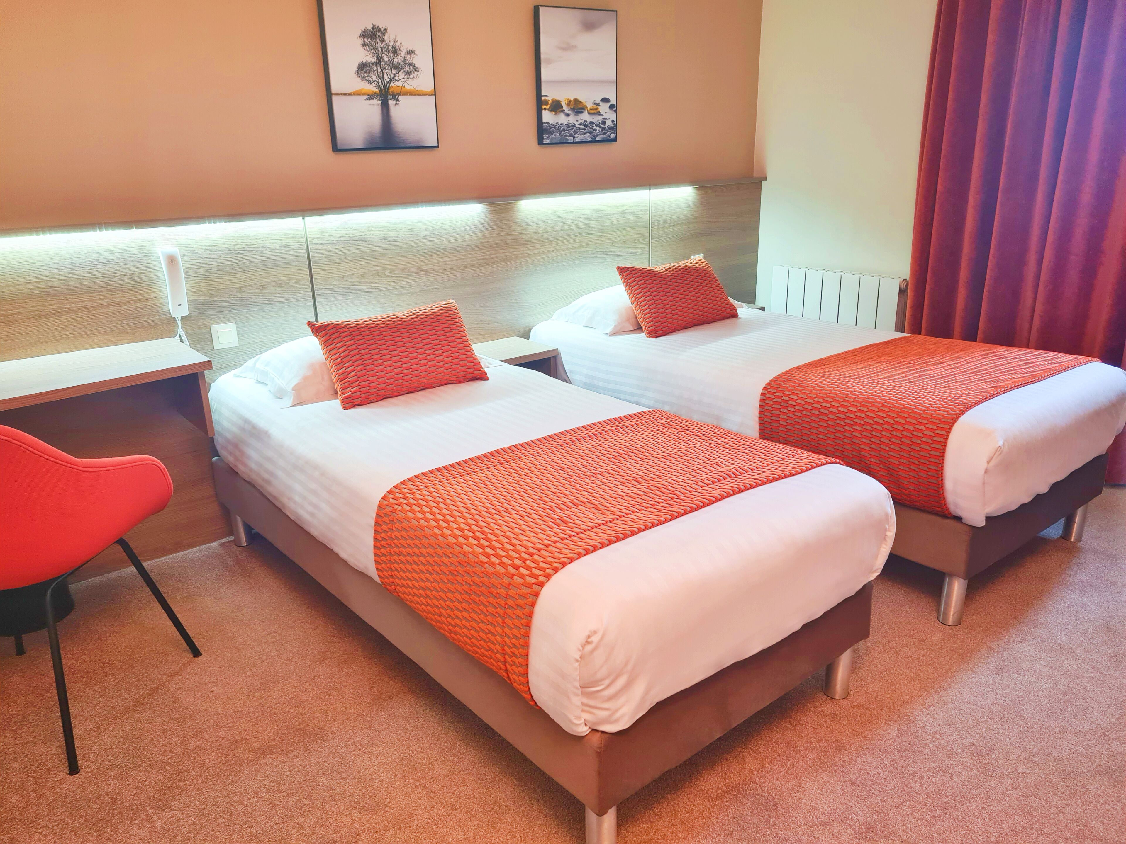 Une chambre d’hôtel avec deux lits, un bureau et une chaise.