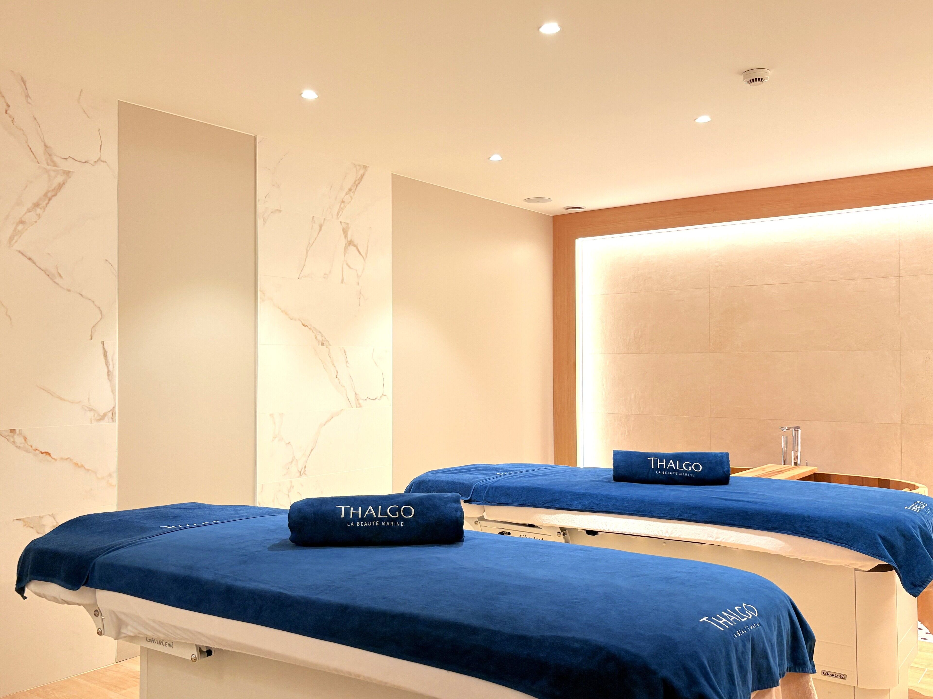 Een spa ruimte met twee behandelbedden, elk bedekt met een blauwe Thalgo deken.