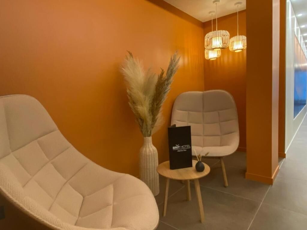 Eine moderne Hotelhalle mit einer gebogenen Couch, einem kleinen runden Tisch mit einem Schild und einer Vase mit Pampasgras.