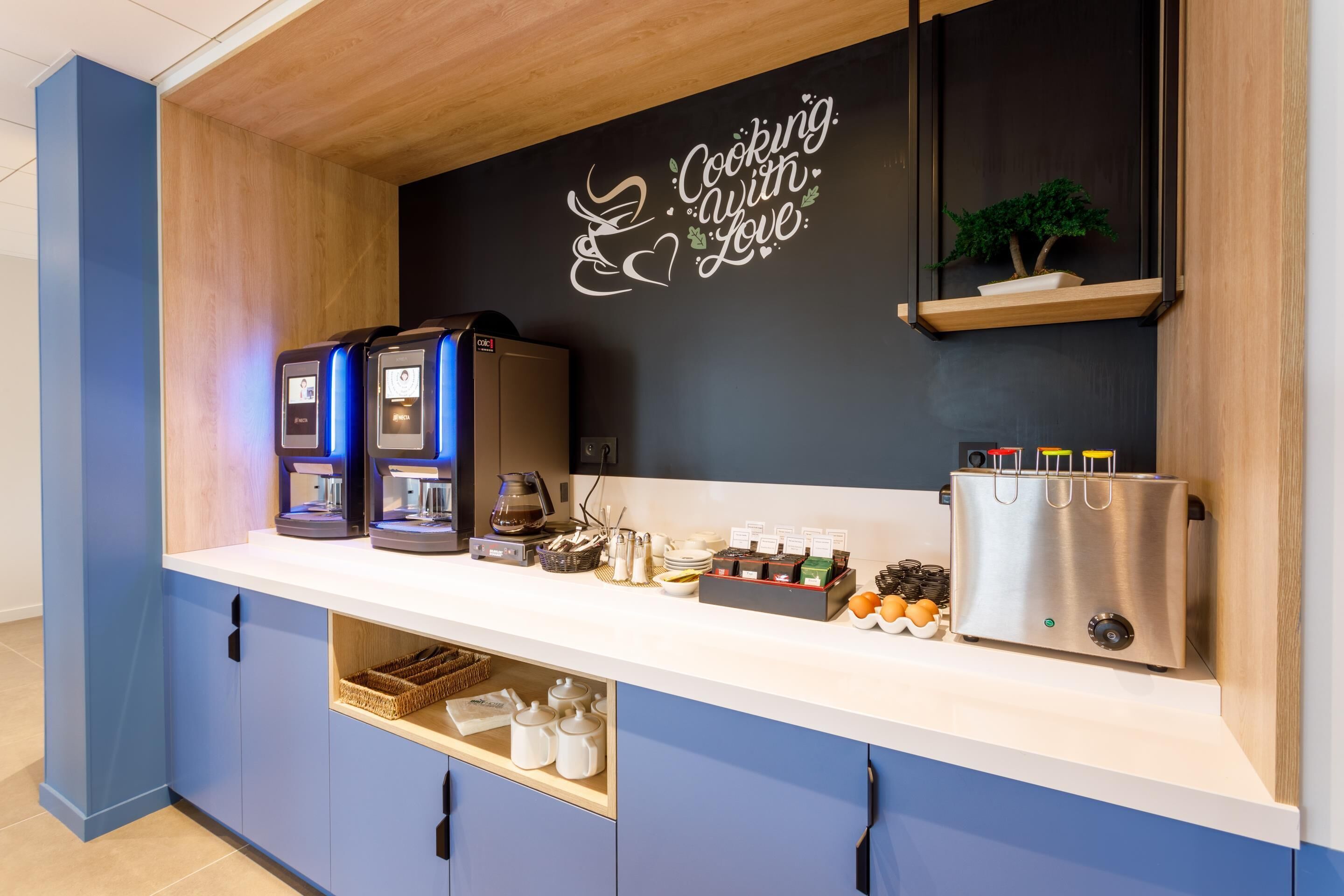 Une petite cuisine équipée d’une machine à café, d’un grille-pain et d’une pancarte sur laquelle on peut lire : « Cuisinez avec amour. »