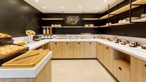 Una cocina moderna con encimeras blancas, armarios de madera y un elemento decorativo en la pared.