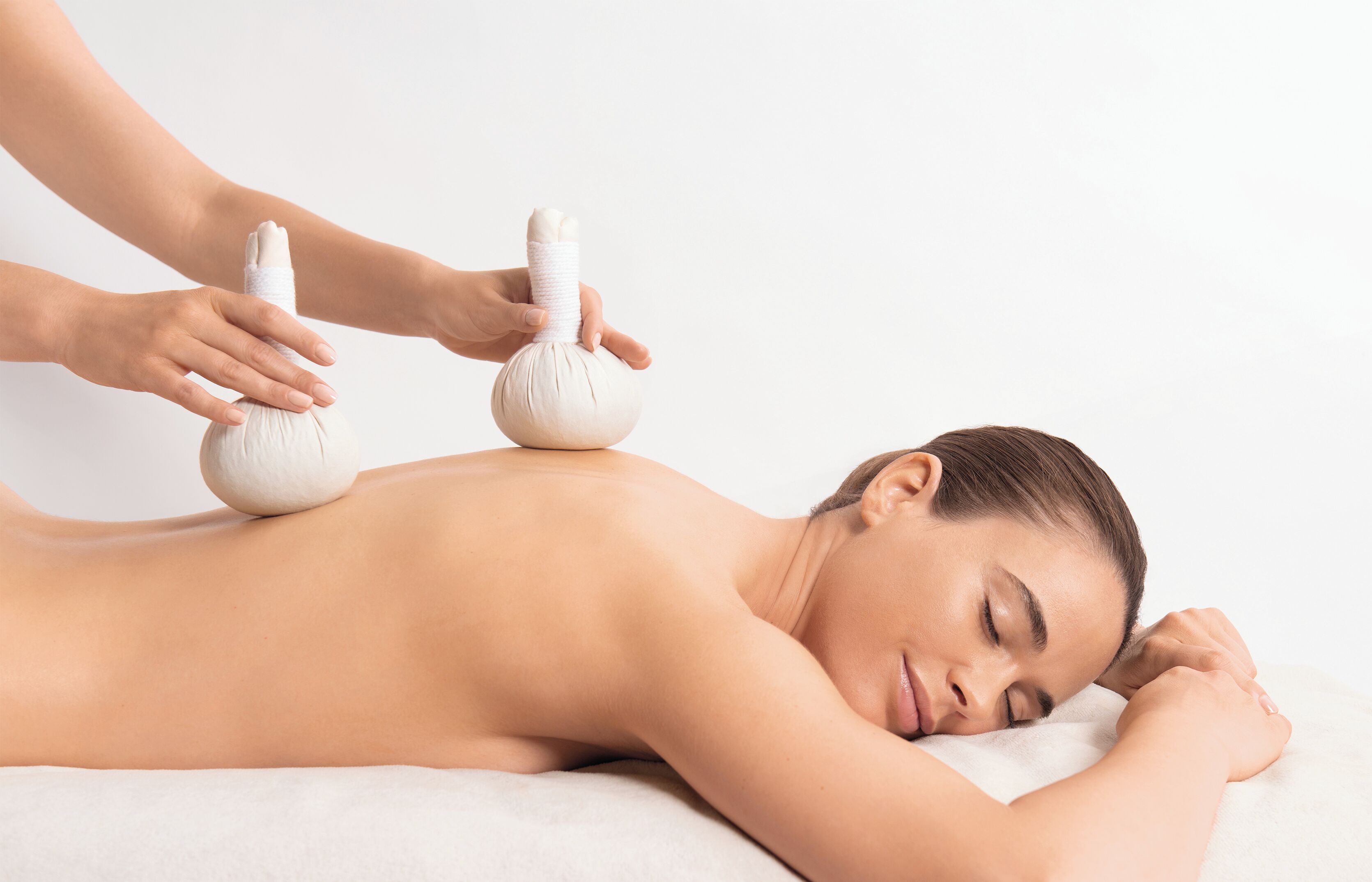 Eine Person erhält eine Massage mit zwei Massagebällen auf dem Rücken.