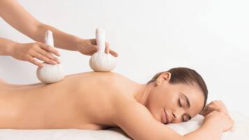 A person receiving a massage with two massage balls on their back.