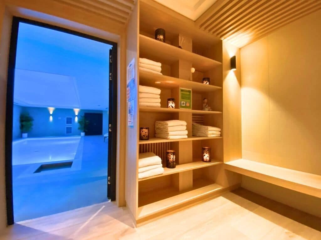 Une chambre d’hôtel avec une étagère en bois contenant des serviettes pliées et des bougies.