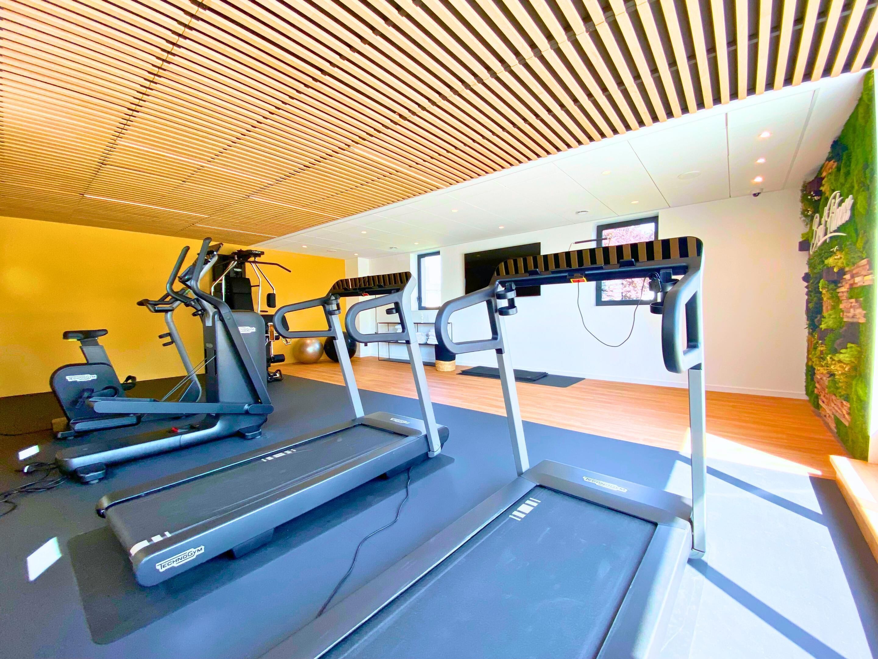 A gym with treadmills, exercise bikes, and a wall-mounted TV.