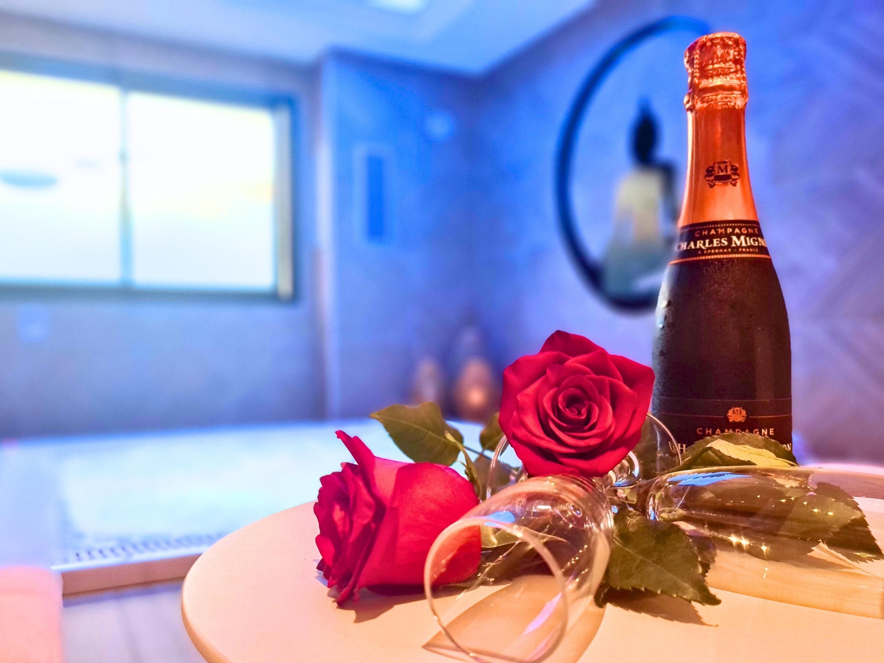 Una botella de champán Charles Mingre, una rosa roja y una copa sobre una mesa.
