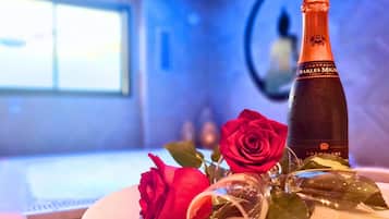Una botella de champán Charles Mingre, una rosa roja y una copa sobre una mesa.