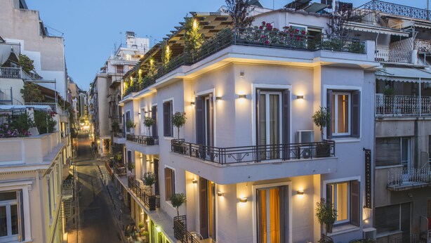 A multi-story building with balconies, outdoor seating, and a narrow street. - Kimon Athens Hotel (Athens)