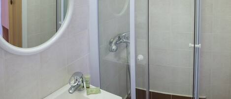 A bathroom with a sink, mirror, and glass-enclosed shower.