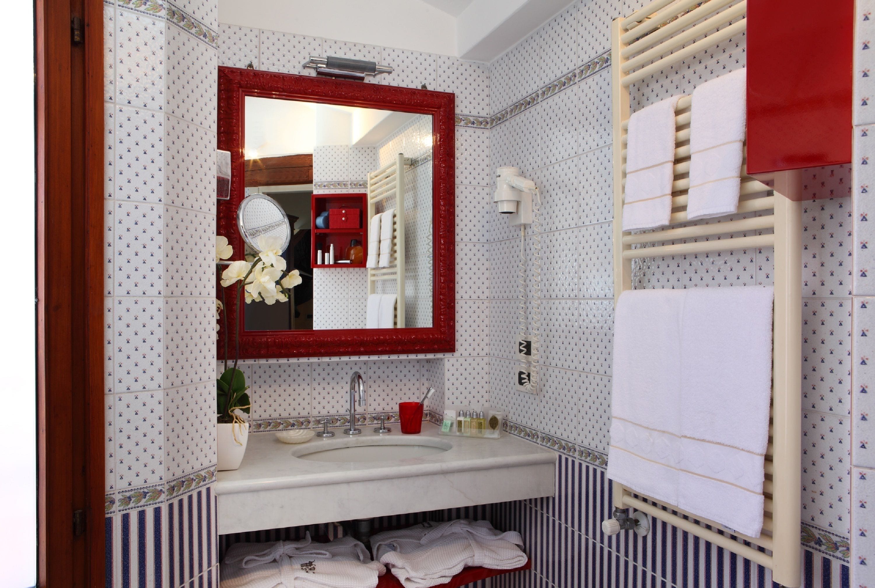 Une salle de bain avec un grand miroir, un lavabo et un porte-serviettes.