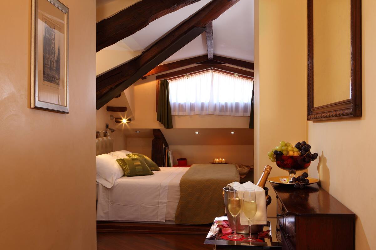 A bedroom with a bed, a nightstand, a dresser, a window with curtains, and a fruit bowl on the dresser.