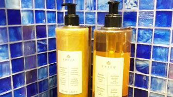 Two bottles of PRIJIA shampoo and conditioner against a blue mosaic tile wall.