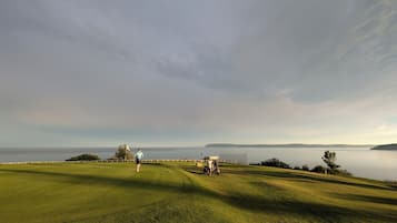 Enjoy a serene golfing experience with a clear view of the water and distant landforms.