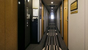 Un pasillo de hotel con piso alfombrado, un teléfono y un letrero que indica los números de las habitaciones.