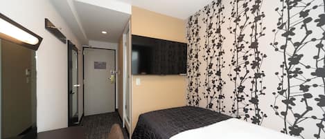 Habitación de hotel con una cama, un televisor en la pared, una puerta y un papel tapiz estampado.