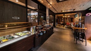 A buffet area with various food options, a bar area with stools, and a view into a dining area with tables and chairs. - APA Hotel Kyoto Eki Horikawadori (Kyoto)
