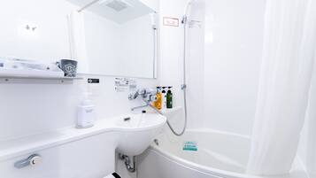 A modern bathroom with a white sink, a mirror, a shower, and a toilet. There are toiletries on the sink counter.