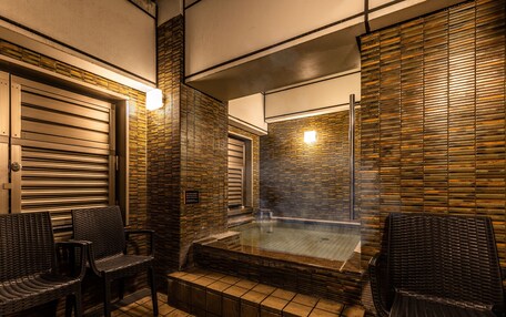 A spa area with a hot tub, wicker chairs, and tiled flooring.
